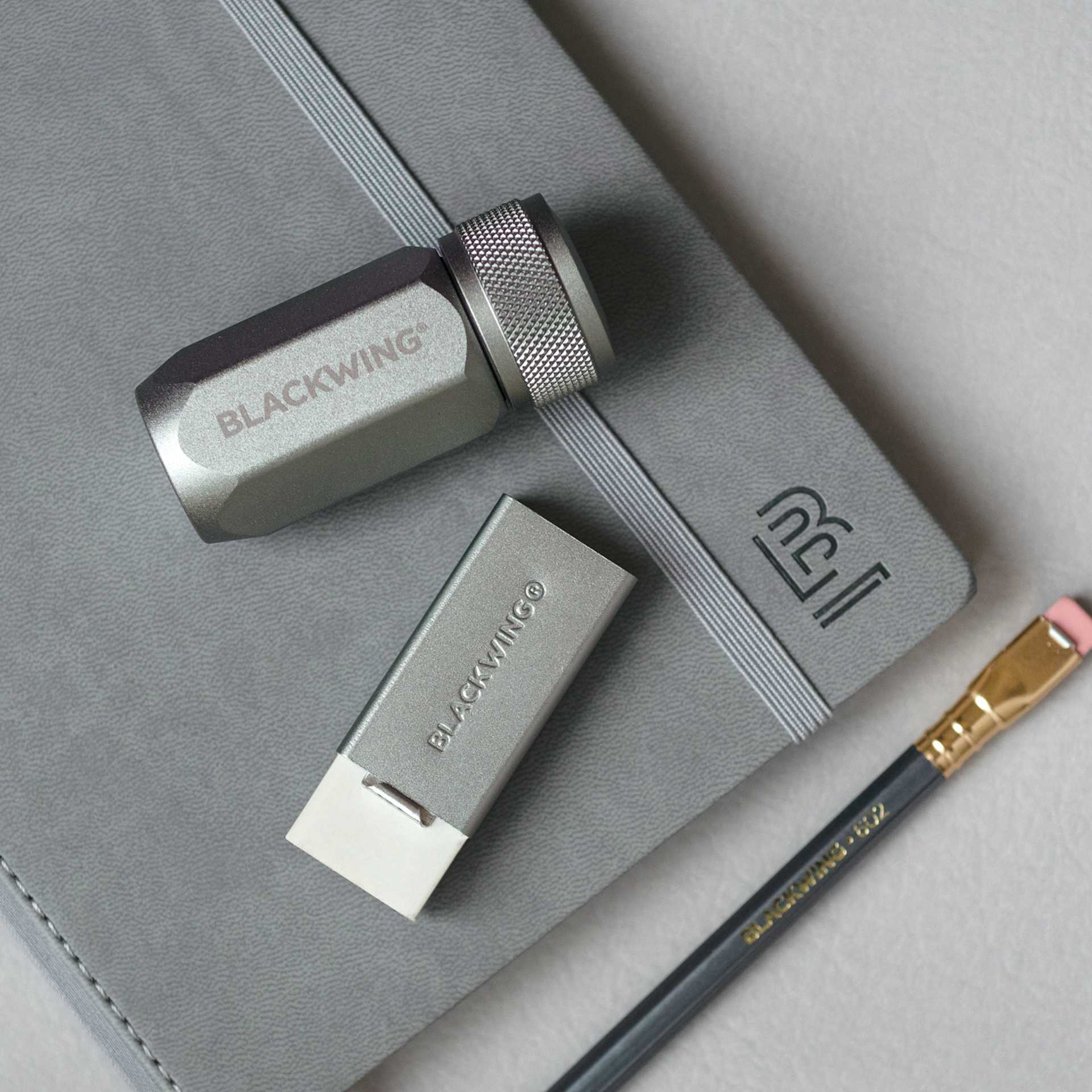 Blackwing Handheld Eraser with Grey Holder, next to pencil, notebook and sharpener (not included) Blackwing Handheld Eraser with Grey Holder, next to pencil, notebook and sharpener (not included)