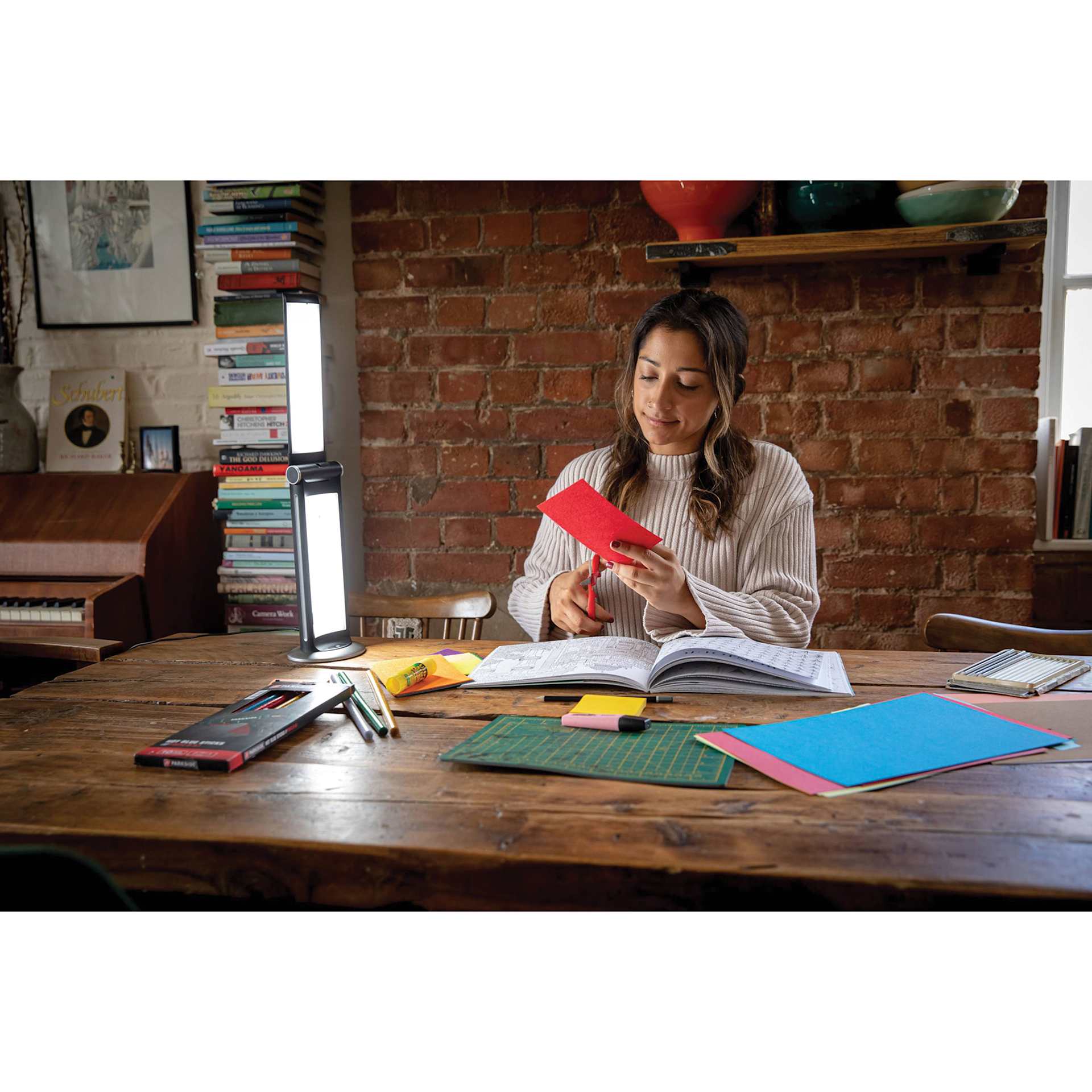 Daylight TwoSun Light Therapy Task Lamp, fully extended and facing adult doing crafts