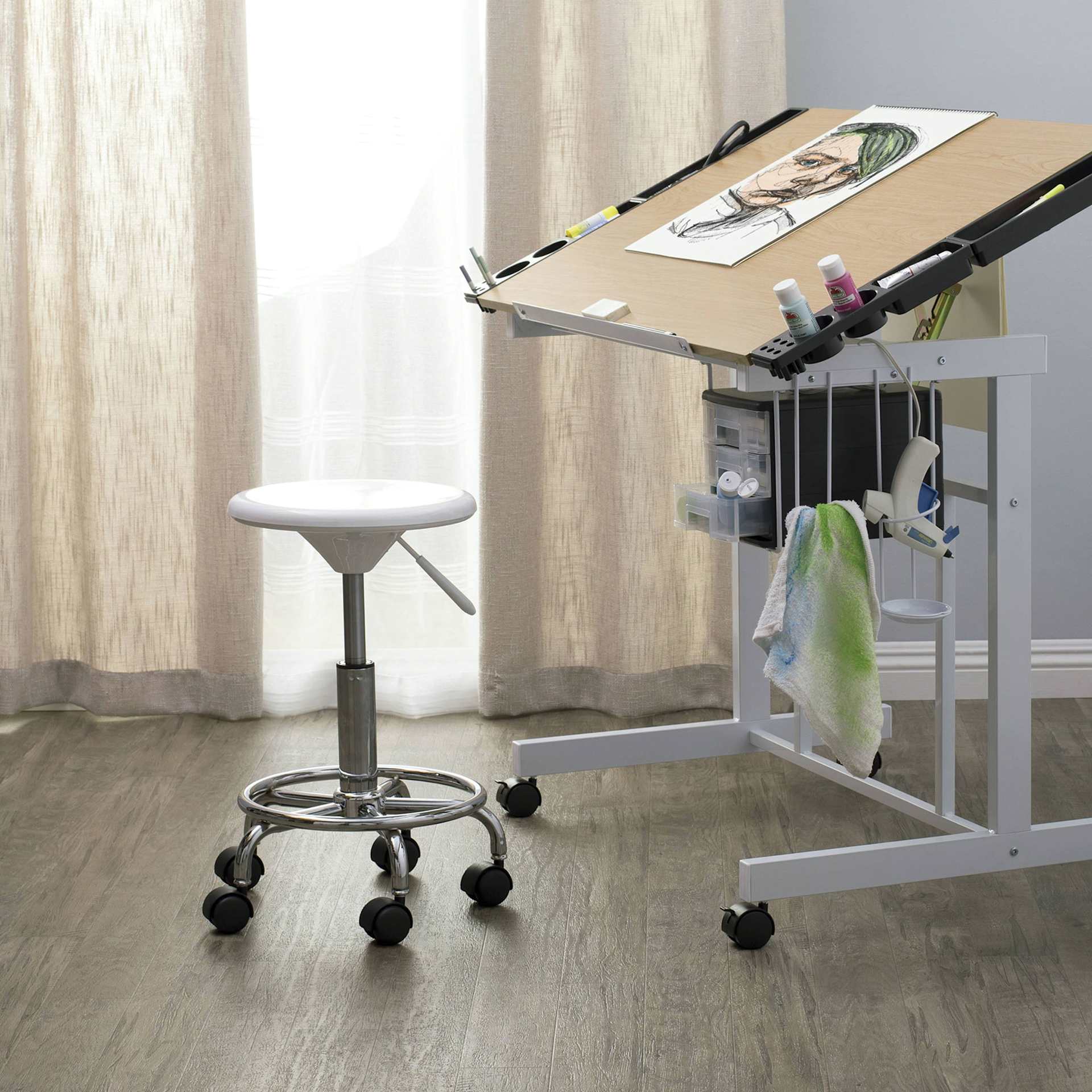 Studio Designs Studio Stool, in front of a drafting table stationed in a room Studio Designs Studio Stool, in front of a drafting table stationed in a room