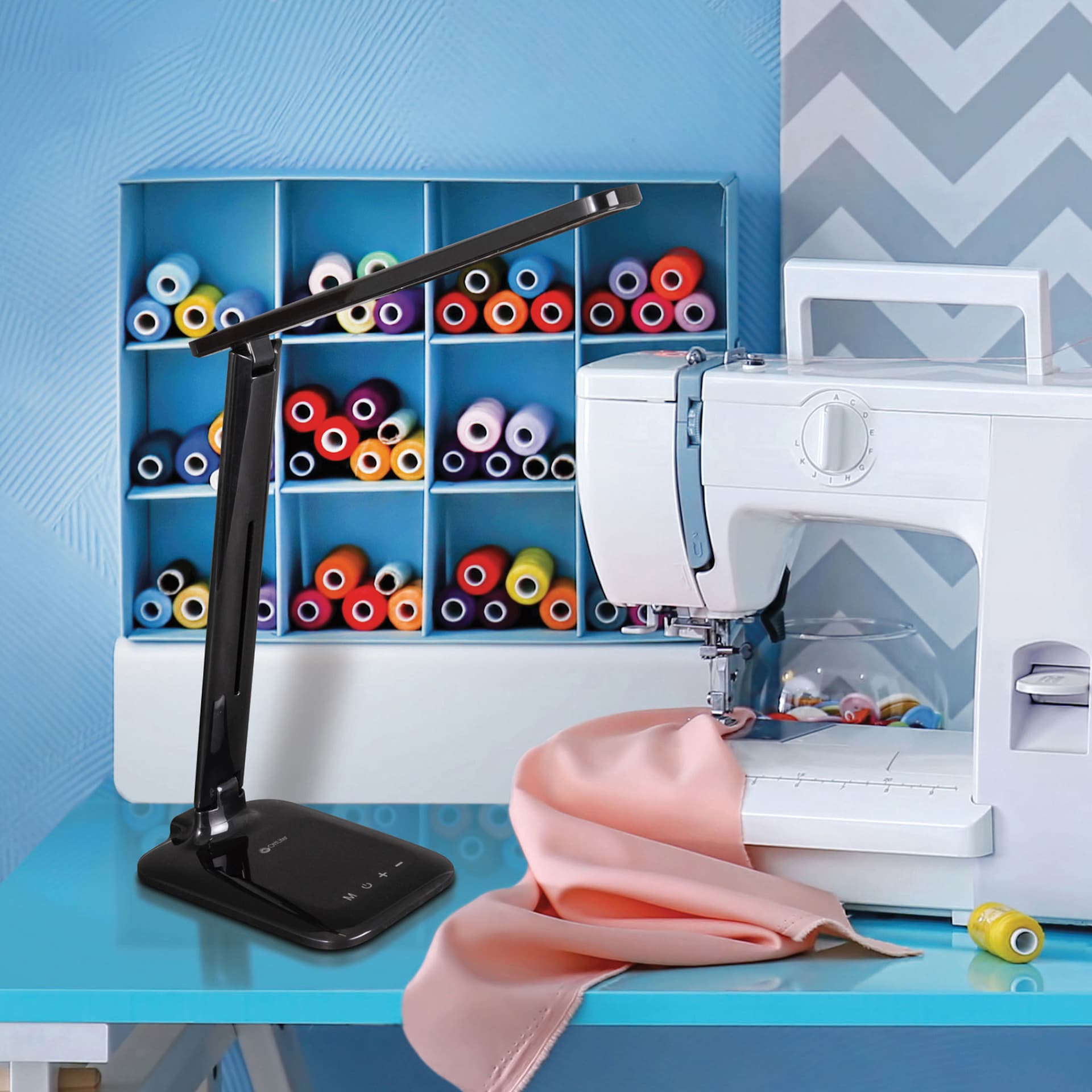OttLite Slimline LED Desk Lamp - Black, to the left of a sewing machine