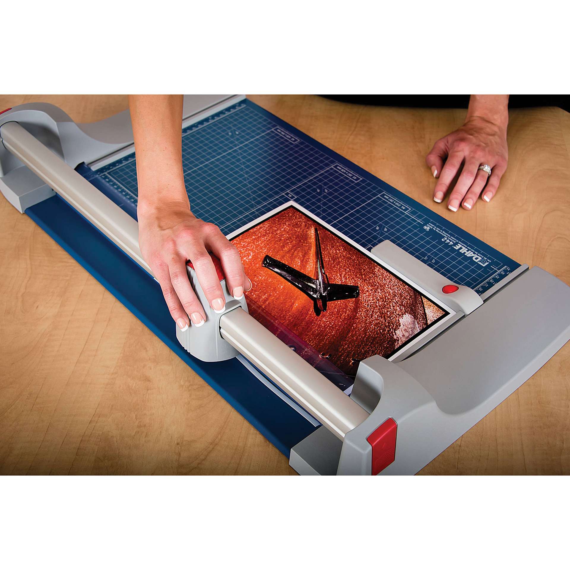 Dahle Premium Rotary Trimmer, adult hand pulling blade across photograph