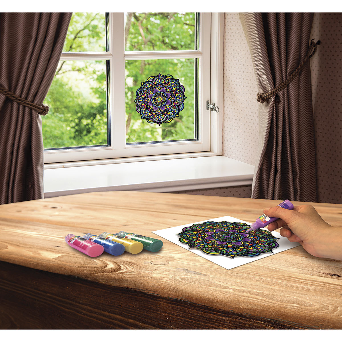 Stain Glass Window Art Cling Kit - Artist painting mandala at table with finished mandala in window