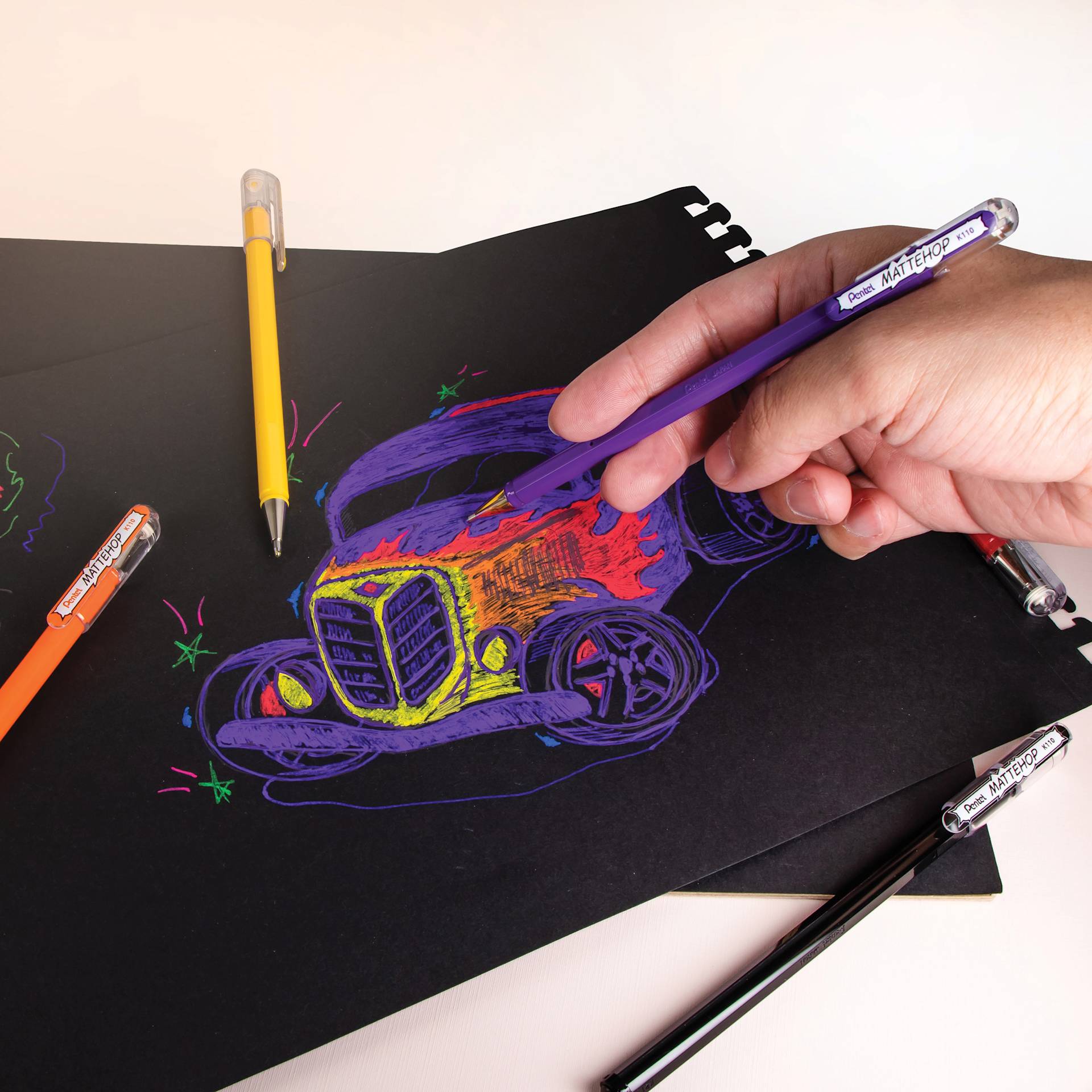 Pentel Arts Hybrid Mattehop Gel Roller Pens, pen in hand drawing a car on Black paper Pentel Arts Hybrid Mattehop Gel Roller Pens, pen in hand drawing a car on Black paper