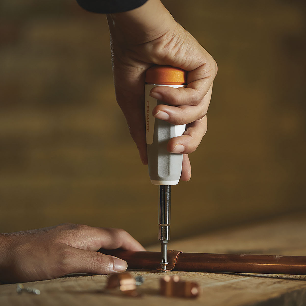 Fiskars Precision Screwdriver - Hand attaching pipe to surface with Screwdriver
