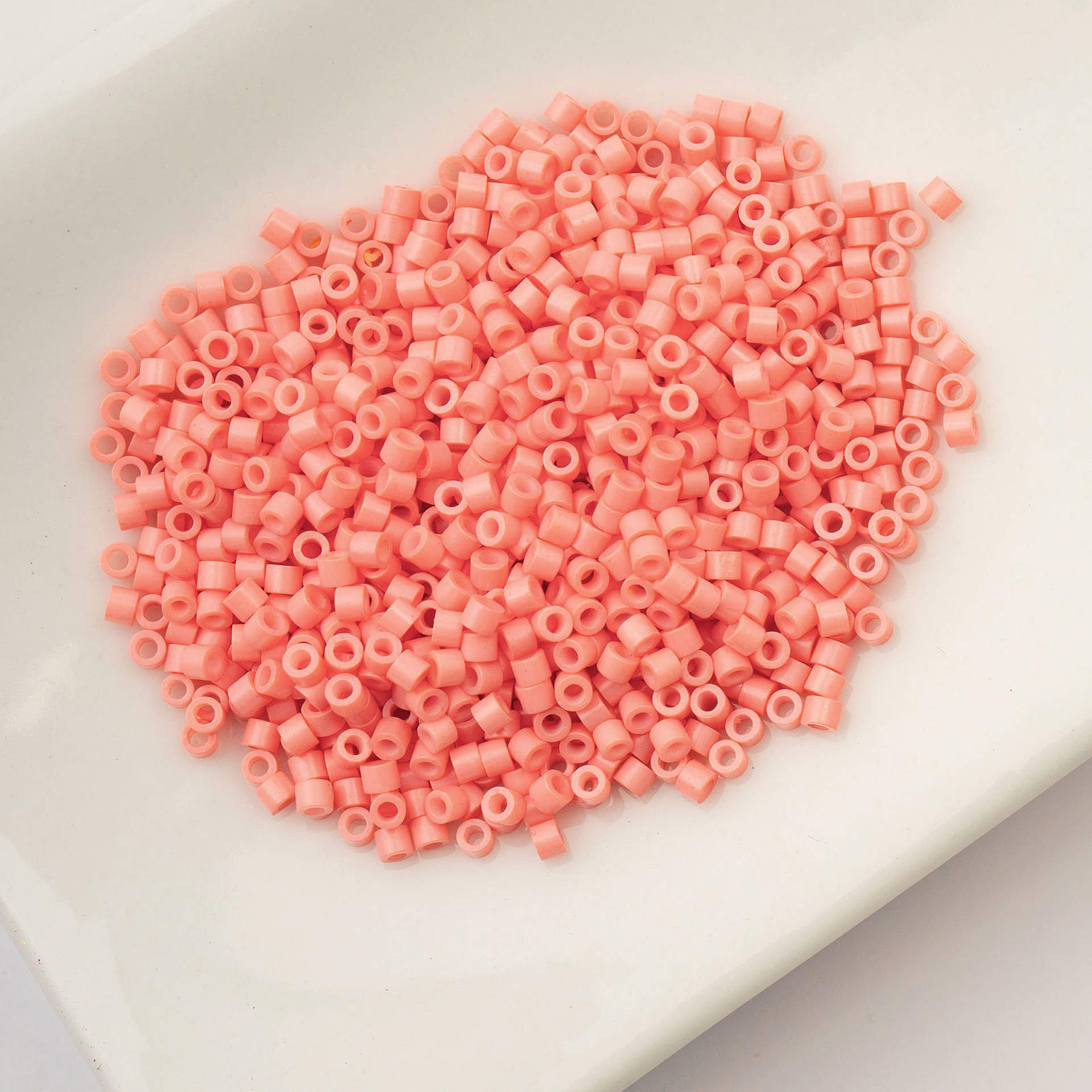 John Bead Cylin 11/0 Cylindrical Seed Beads - Soft Coral Pink Opaque sitting in dish