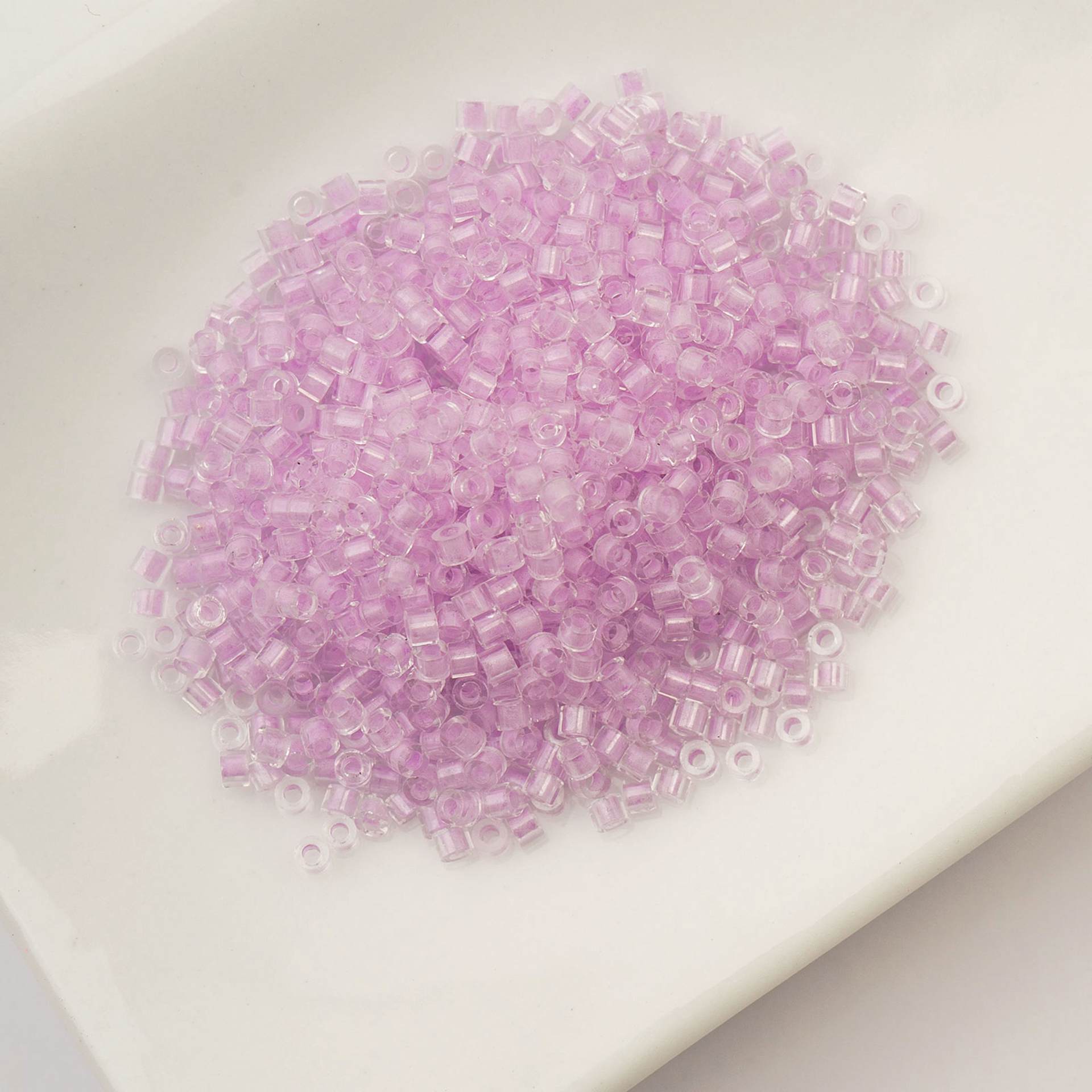 John Bead Cylin 11/0 Glow in the Dark Cylindrical Seed Beads - Violet, 25g sitting in dish
