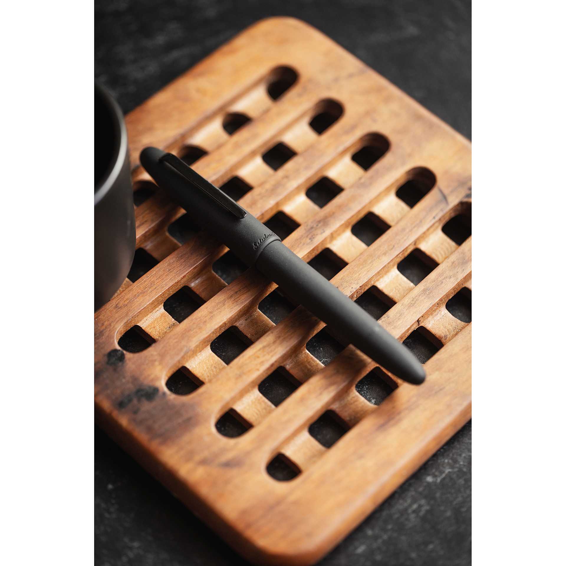 Esterbrook Estie Fountain Pen - Raven Matte Black, resting on wooden coaster