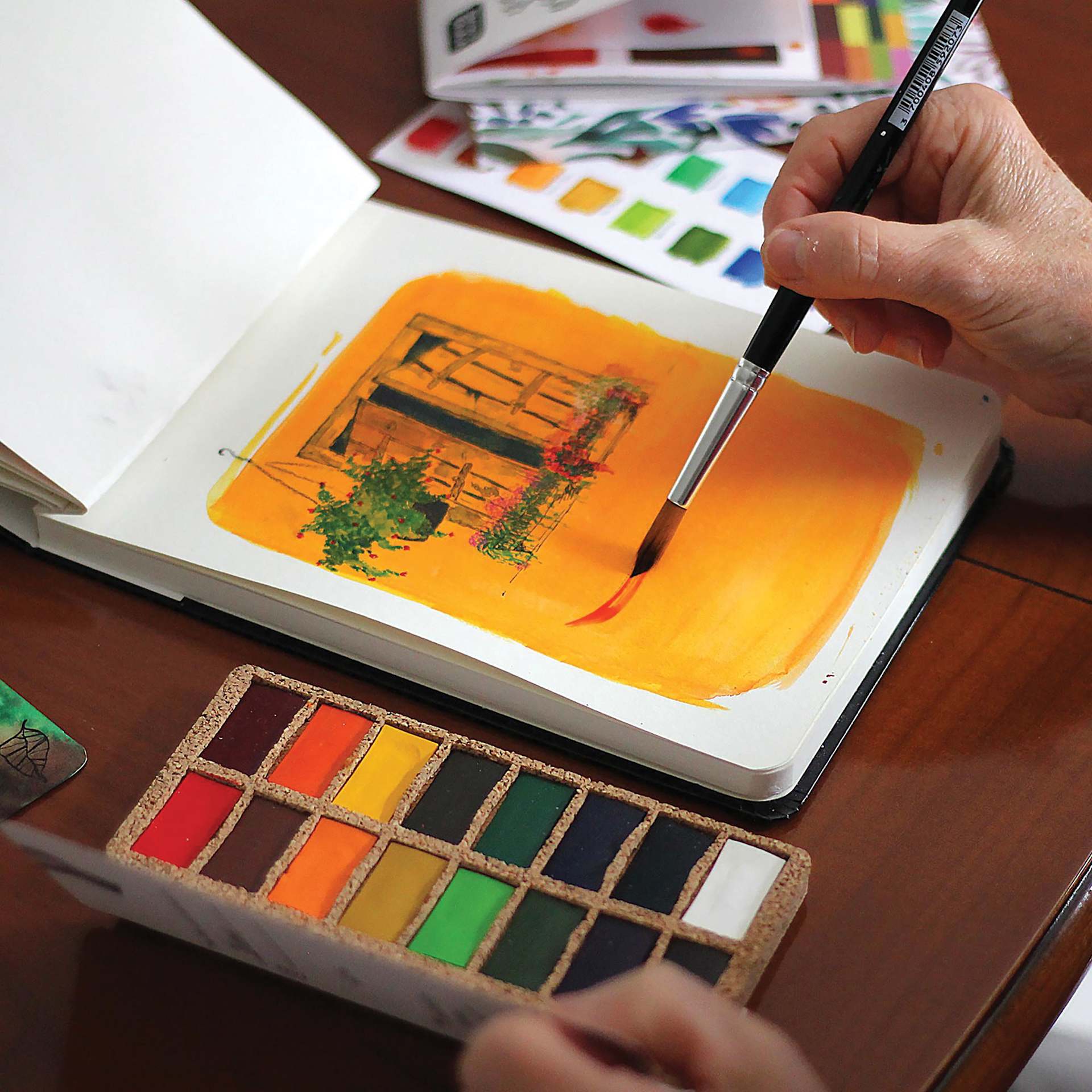 Viviva Watercolor Paint Pan Set - Original, Set of 16 being used with a sketchbook.