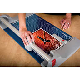Dahle Premium Rotary Trimmer, adult hand pulling blade across photograph