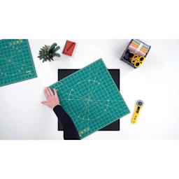 Olfa Rotating Cutting Mat - 12" x 12" - demonstration of the self-healing mat being rotated on the non-slipping mat