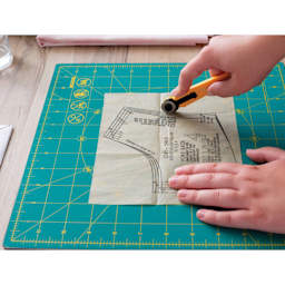 Olfa Rotating Cutting Mat - 12" x 12" - knife in hand cutting a design template on mat