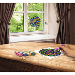 Stain Glass Window Art Cling Kit - Artist painting mandala at table with finished mandala in window
